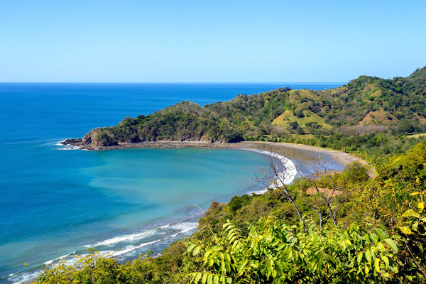 Scenic tropical bay with turquoise water white sand beach and lush green hillsides showing pristine family-friendly coastal destination