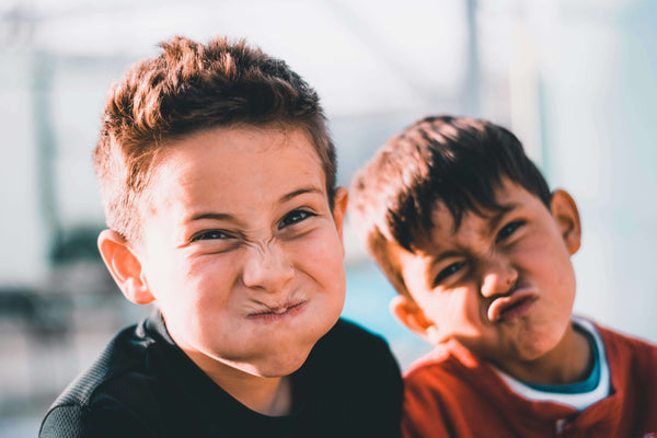 Two young boys making silly scrunched-up faces at camera showing playful sibling or friend dynamic during family travel