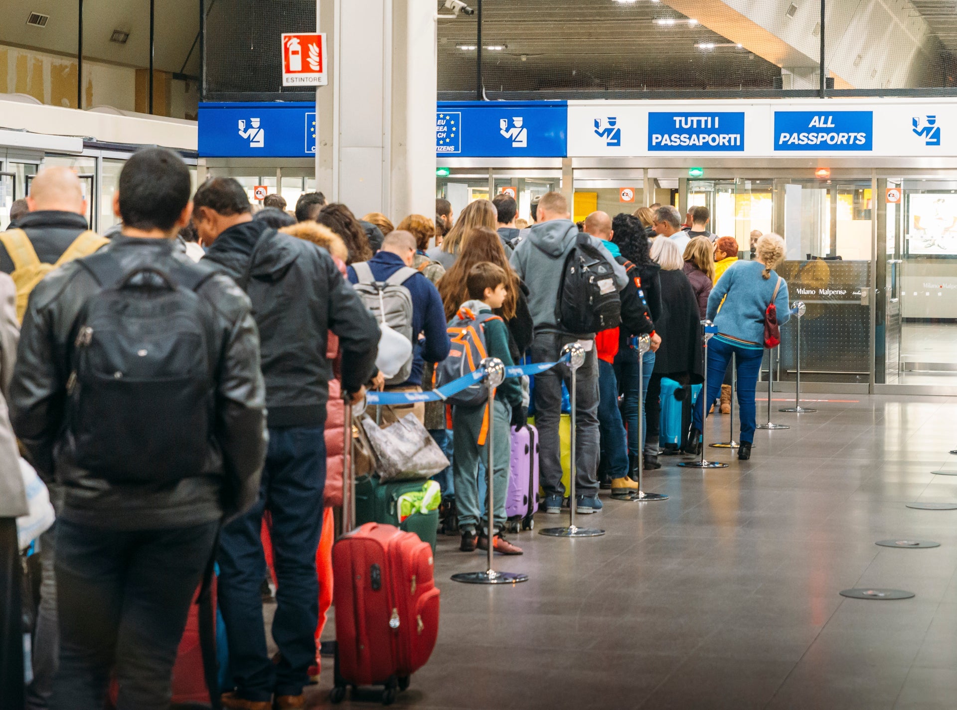 Long queue of travelers with luggage waiting at airport passport control