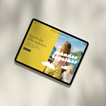 Tablet displaying WeeWander website homepage with yellow hero section and beach family photo showing travel planning topic